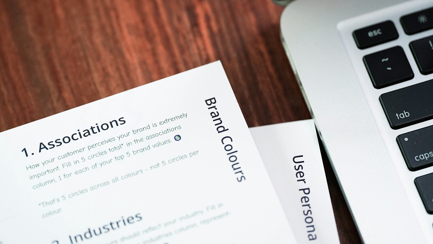 Brand strategy documents lie on a wooden office desk.