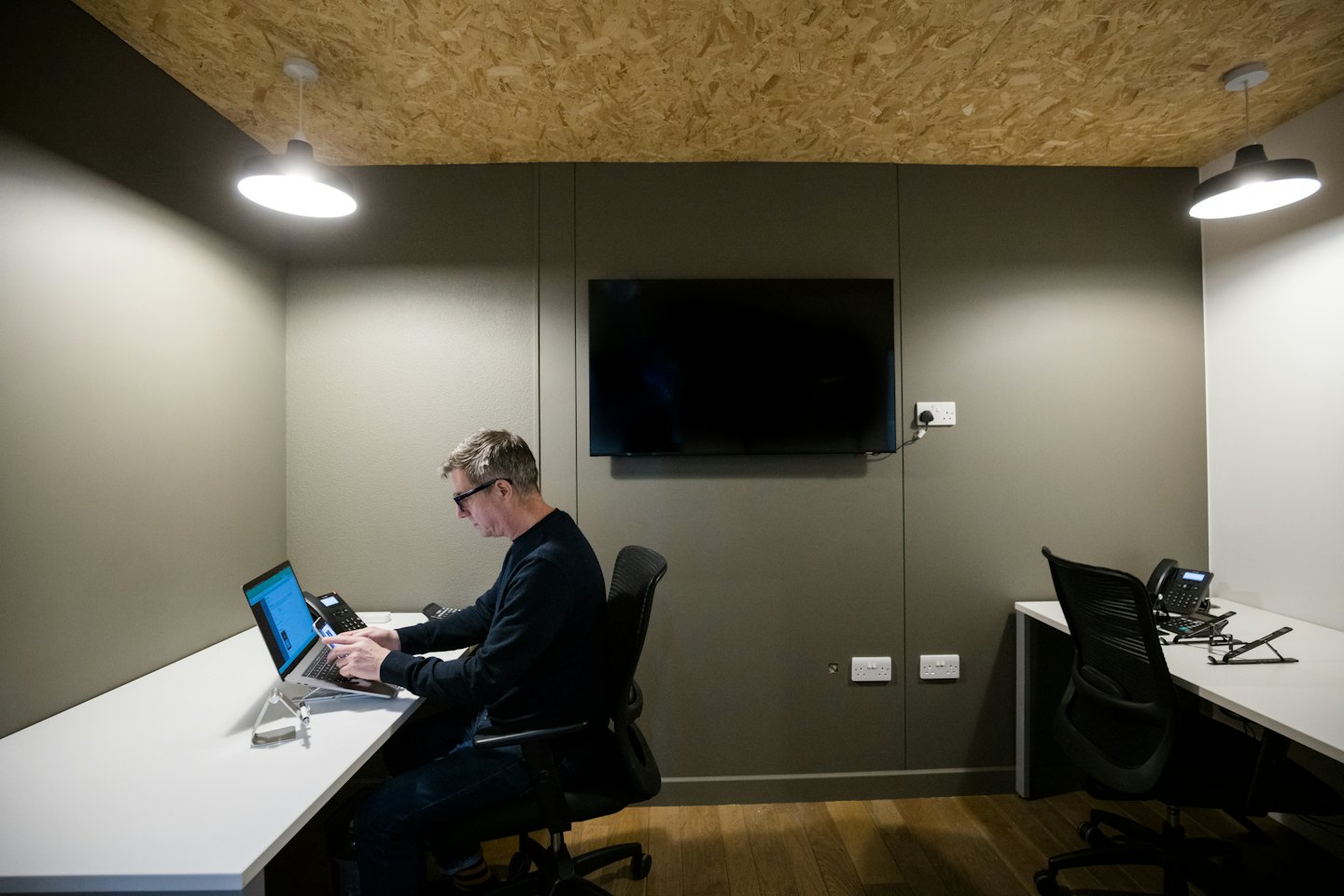 Man working on laptop at a white desk in modern office.
